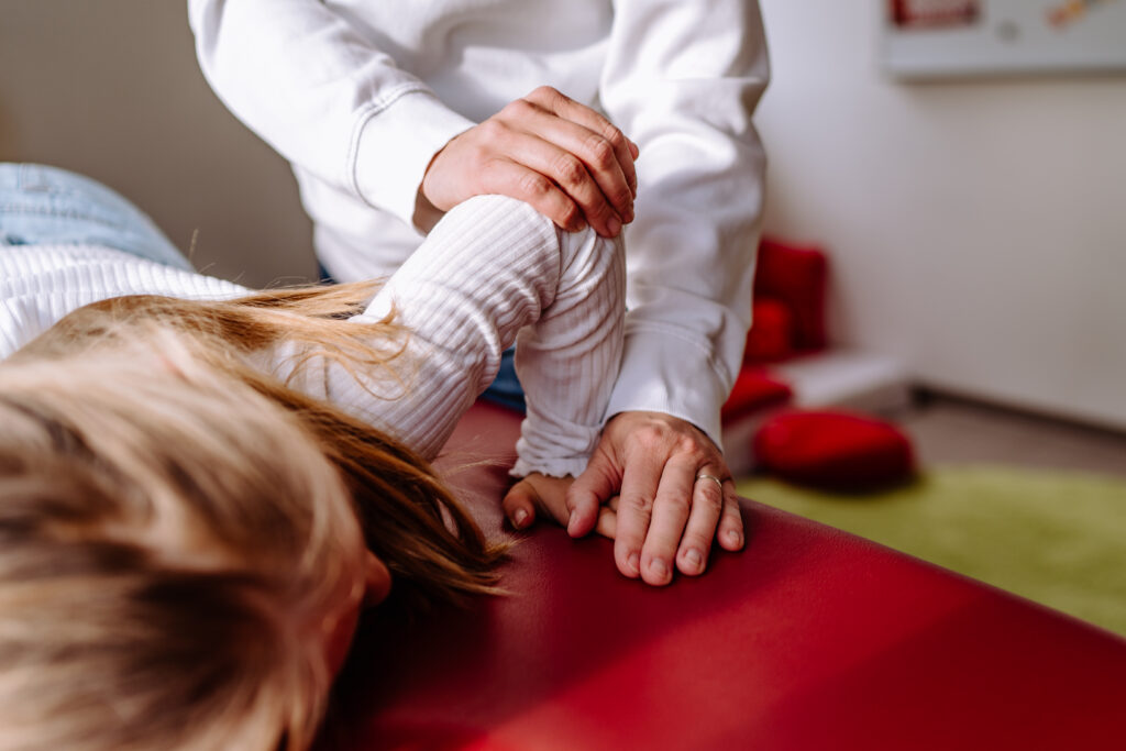 Therapeutin gibt leichten Druck auf angewinkelten Arm.