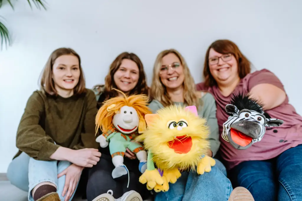 4 Frauen lachen im Hintergrund und haben drei Kuscheltiere in den Händen
